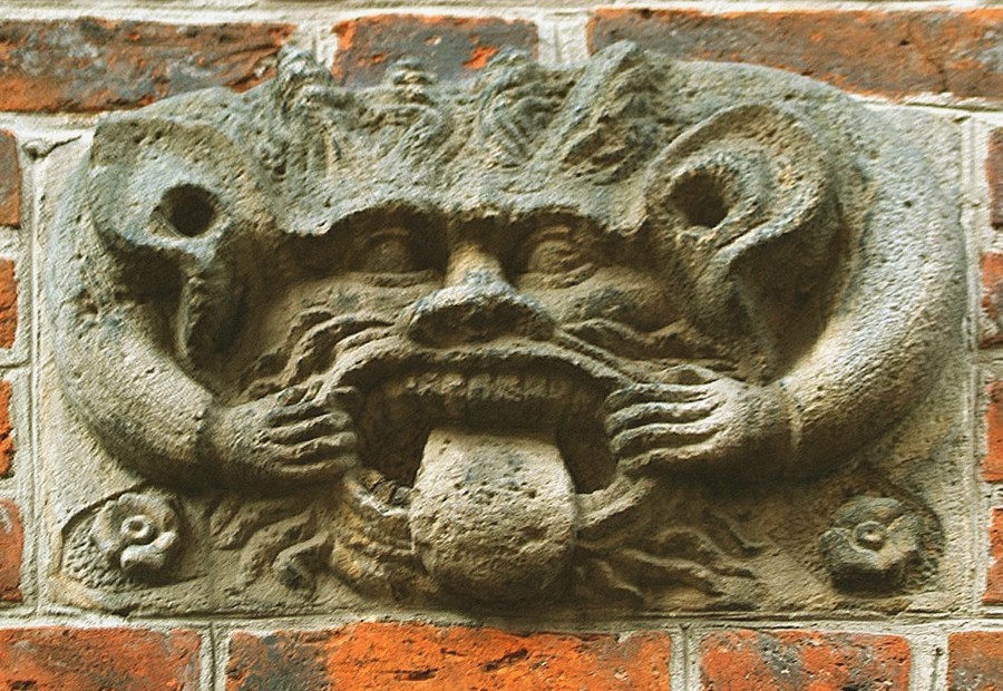 Im Mauerwerk des Alten Rathauses in Hannover weist eine eiserne Öse auf den Ort, wo die Angeprangerten angekettet wurden. Gleich daneben grinst die Steinfratze und streckt die Zunge heraus.